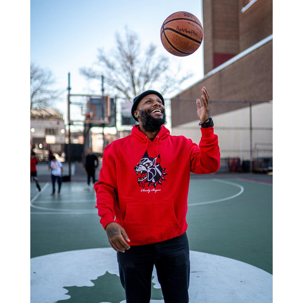 Red Charly Bryan Big Dog hoodie worn by a person holding a basketball outdoors.